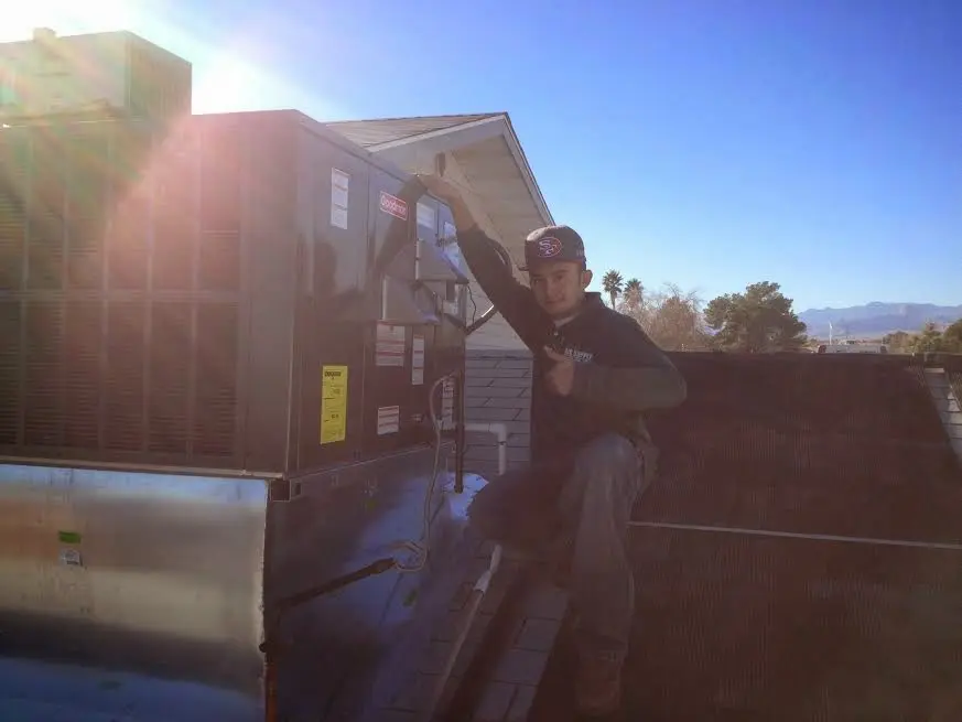 HVAC technician performing AC Tune-Up on a rooftop unit in Urbandale